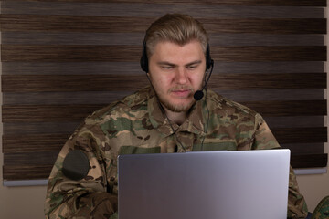 Man in military uniform using laptop outdoors
