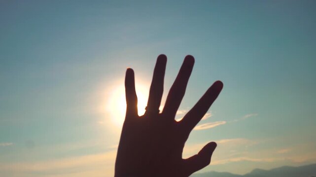 Silhouettes of hands with Sun Rays Through Human Hand at Sunrise. Sunset scenery