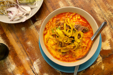 Traditional Thai noodle soup served with fresh garnishes on a rustic wooden table