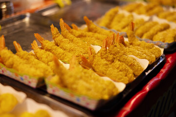 Golden fried shrimps arranged for display in a vibrant street food market