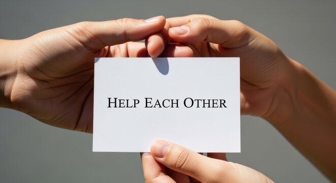 Hands holding a card with the message help each other. Community support, cooperation, and volunteering concept for international volunteers day