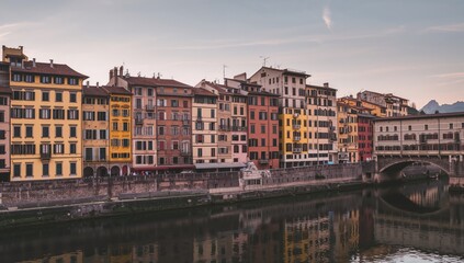 Obraz premium Dawn over the river with vibrant historic stone buildings lining the waterfront