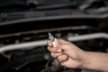 Fototapeta premium Close-up of a man’s hand holding a car spark plug, representing automotive maintenance, mechanic work, vehicle repair, and engineering technology.