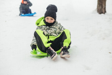 Kids sledding in snowy winter park fun