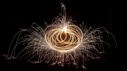 Long exposure shot of sparking light trails creating a glowing orb against black