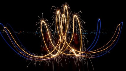 Bright, looping trails of light from sparks, against a stark black background
