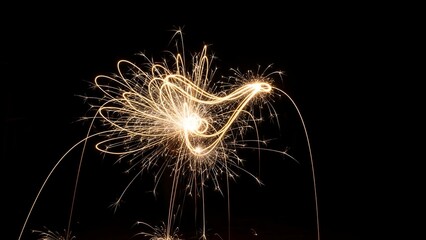 Bright, glowing trails of light, creating an abstract display against a stark, black backdrop