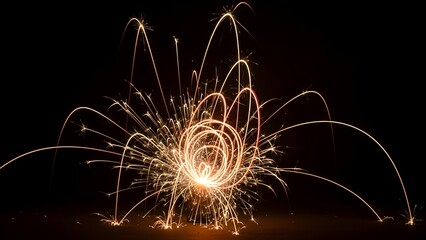 Close-up of glowing sparks emanating from a central point against a stark, black background