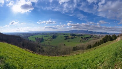 Obraz premium Scenic rural landscape with lush green fields and gentle hills on a bright spring day