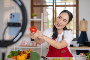 Woman vlogging healthy cooking showing fresh tomato