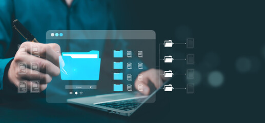 Businessman using laptop with digital folder icons on virtual screen, representing cloud data management, document storage, and modern information organization technology.