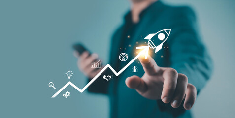 Businessman pointing at rocket icon on growth graph, symbolizing startup success, innovation,...