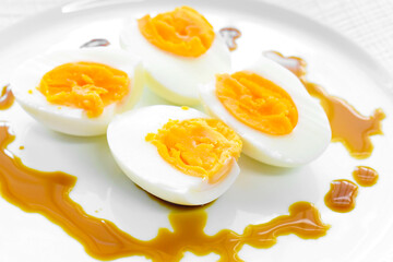 Boiled egg with soy sauce on a white plate. Healthy and dietary food.