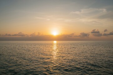 Naklejka premium Wide-angle view of a serene seaside with gentle waves and a glowing sunset