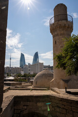 Fototapeta premium Ancient Tower and Modern Skyscrapers Under Sunny Sky. Baku Cityscape with Flame Tower