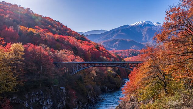 Bridge spanning a colorful mountain gorge filled with autumn maple trees on a bright sunny day