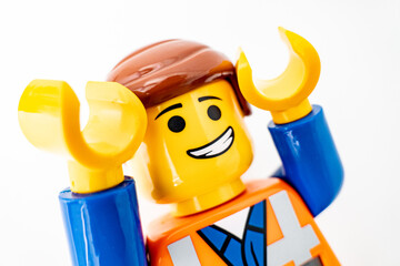 Naklejka premium Bradford, UK Oct 30 2025 - Lego Emmet plastic toy shot close up on a white background. Both arms raised in a look of suprise