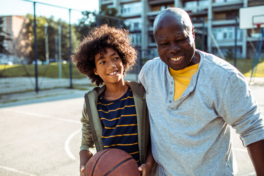 Grandfather playing basketball with grandson outdoors