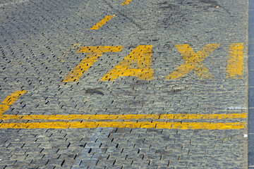 Taxi sign on dirty cobble stone street pavement in city outside