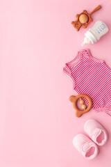 Flat lay of baby bodysuits and eco friendly accessories - booties, wooden rattle toy and baby...