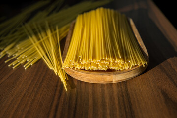 Uncooked spaghetti on wooden tray with sunlight