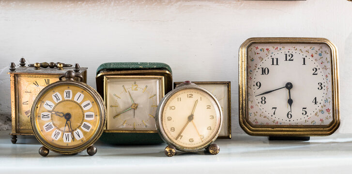 Vintage clocks and alarm clocks placed on a shelf, white background, frontal view