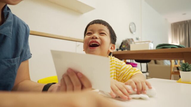 Asian mother and little son learning with flashcards during homeschool at home, smiling and practicing words together in a fun and relaxed.