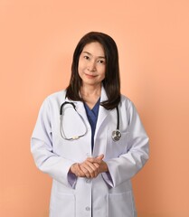 Portrait of asian female doctor in medical uniform with stethoscope on peach color background.
