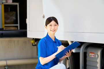 トラックの前で点検する女性作業員　配送