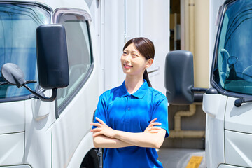 トラックと腕組みする女性ドライバー