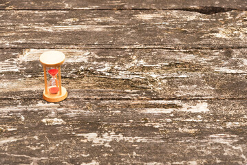 Flat lay (top view) of a vintage hourglass on rustic wood table. Natural daylight. Ample copy space right. Symbolizes time passing, deadlines, waiting, and planning.