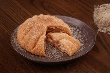 Naklejka premium Single Traditional Fried Pastry Filled with Chocolate Brazilian Sweet Treat on Wooden Surface