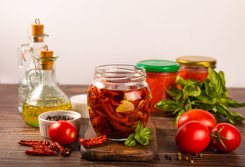 Dried organic tomatoes preservation with herbs and olive oil in jar.