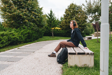 Person relaxing on a bench in a park during a cloudy day