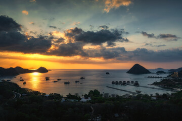Fototapeta premium As day fades to night, warm hues glow across a tranquil bay, showcasing beautiful boat silhouettes and creating a stunning seascape for all to admire, Labuan Bajo, Komodo, Indonesia