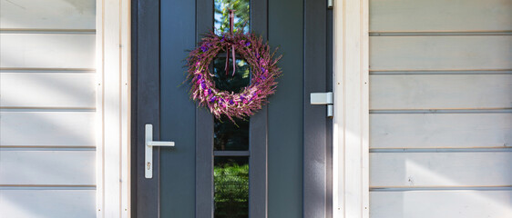 Front door with decorative wreath, seasonal autumn mood, home entrance design, cozy holiday decoration, house facade background, concept of welcoming home, Thanksgiving day. Autumn banner, wide album