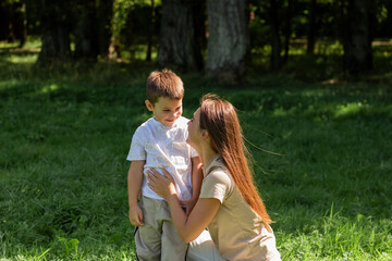 Fototapeta premium Young Caucasian mother laughs giggling son across sunny park lawn. Dynamic image radiates pure joy, energy, and fun of outdoor playtime together.