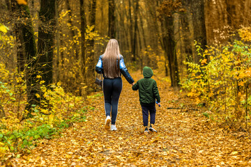 Fototapeta premium Mother and son walking in autumn forest