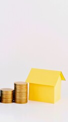 Stacks of coins leading to a yellow house symbolizing financial growth