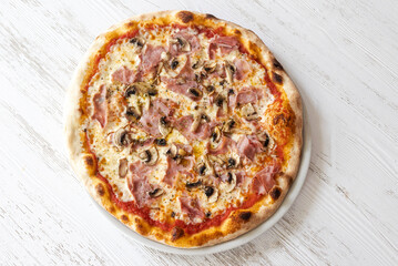 Delicious ham and mushroom pizza on white wooden table