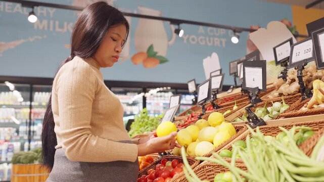 Commercial style image of pregnant Asian woman shopping healthy food in supermarket ideal for maternity wellness campaigns.