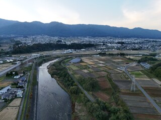 A river runs through a valley with a city in the background. The city is small and has a rural feel to it