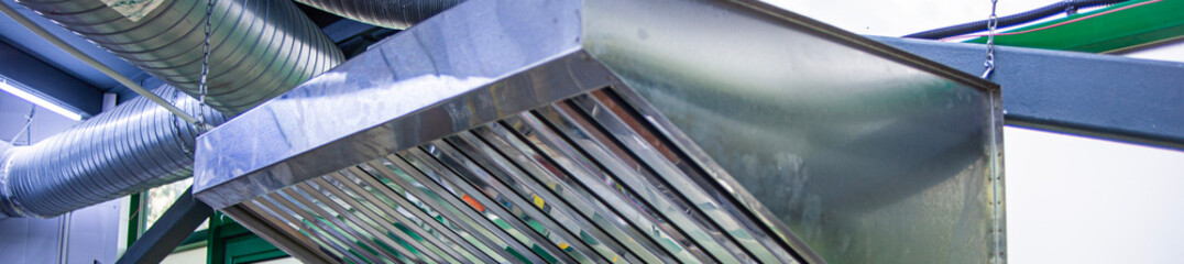 Stainless steel exhaust hood with grease trap close-up in a large industrial kitchen in the...