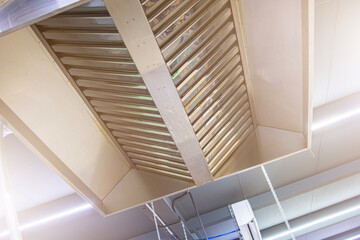 Stainless steel exhaust hood with grease trap close-up in a large industrial kitchen in the...