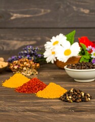 Vibrant Spices and Herbal Arrangement on Rustic Wood Surface with Floral Accents