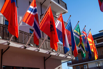 Flags from various countries displayed along a sunny building facade