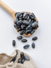 Wooden spoon and burlap bag filled with dried barberries for culinary use.
