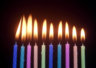 Many colourful birthday cake candles burning on black background