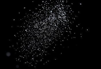 Scattered white particles on dark background with bokeh effect
