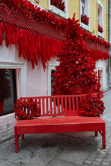 Decorative metal bench in front of a large Christmas tree decorated with red ornaments and...